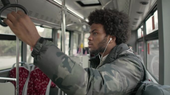 在公交车上，黑人男乘客正在听音乐