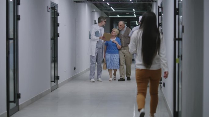 老年夫妇与医生在诊所走廊散步