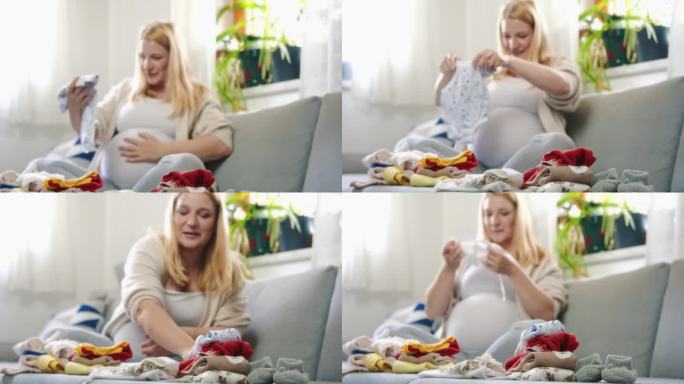 孕妇在家里客厅的沙发上叠婴儿衣服
