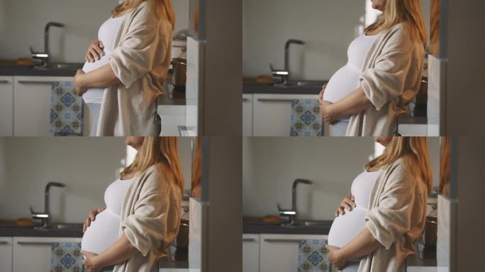 孕妇在厨房里做饭和按摩肚子