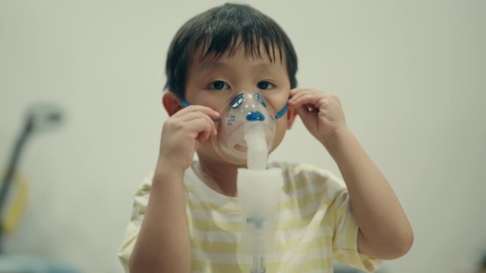 儿童疾病管理:患感冒的亚洲男孩接受雾化器治疗。