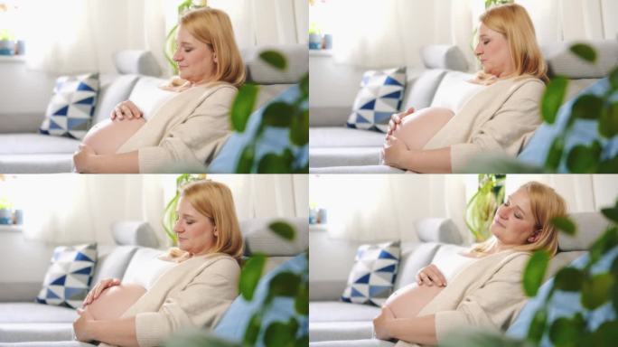 安详的孕妇放松，在沙发上揉着宝宝的肚子