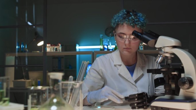 女研究员在实验室显微镜下研究液体