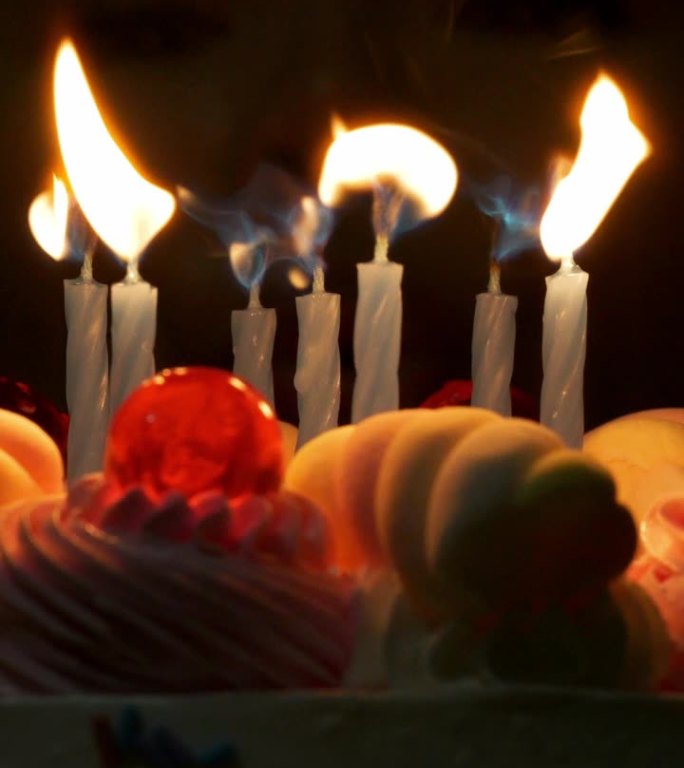 女人吹灭蜡烛，对着生日蛋糕许愿。