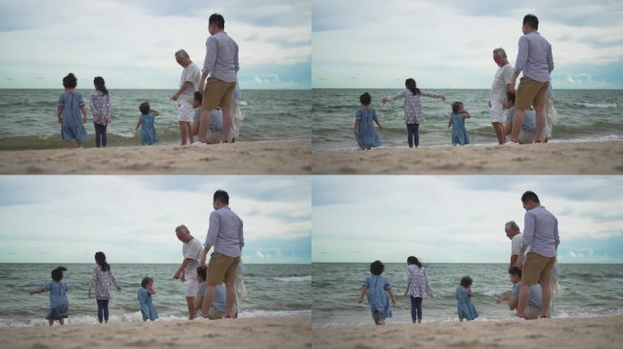 几代同堂的一家人站在沙滩上看美丽的大海。