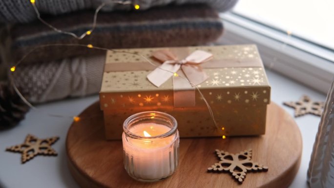 冬天窗台上的静物。礼品盒，燃烧的蜡烛和舒适温暖的毛衣。圣诞节的精神。温馨家居装饰理念。冬日冬日冬日冬