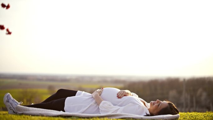 一名孕妇在乡下躺着揉着肚子