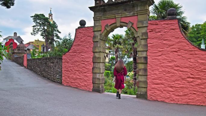 一个穿着红裙子的漂亮女孩参观了波特梅里恩村。