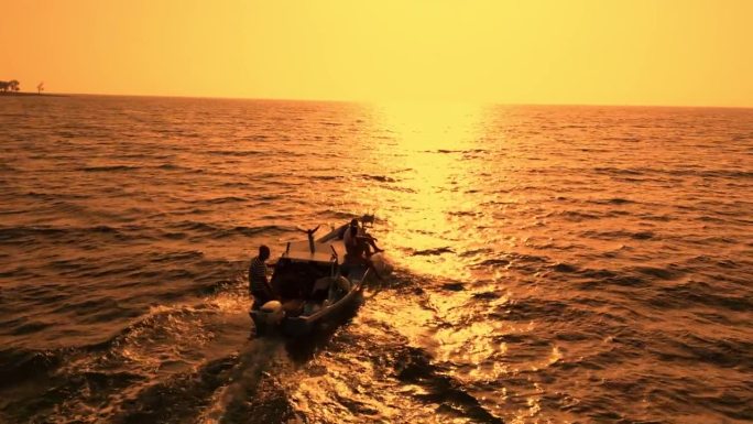 一艘旧木船在海上驶向日落时的地平线