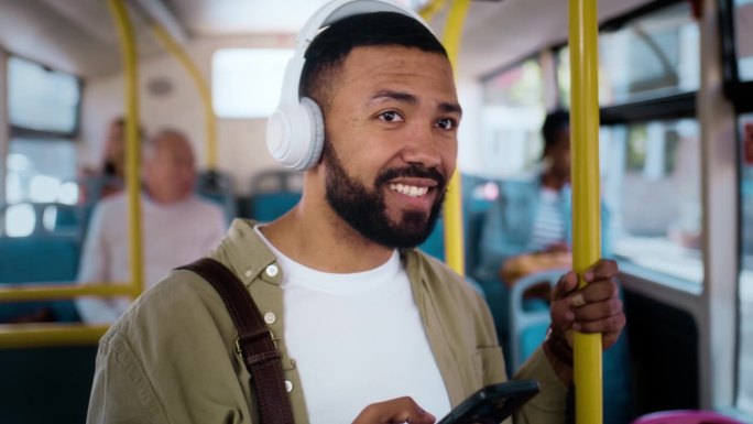 一个快乐的人在公交车上带着手机和耳机，在城市通勤路上开车时带着微笑。公共交通、服务或乘车、智能手机上