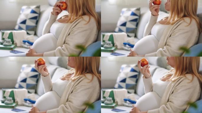 孕妇在家里客厅的沙发上吃红苹果