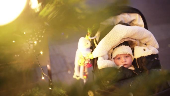 圣诞节期间，奥地利施蒂里亚州格拉茨街头，用高角度手持拍摄可爱的婴儿坐在舒适温暖的婴儿车里