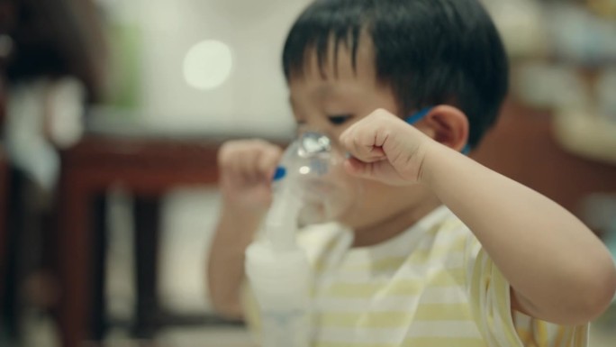 儿童呼吸系统疾病:患病的亚洲男孩在室内接受雾化器治疗。