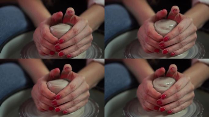 一名妇女用手在旋转的陶工转轮上捏成一团粘土
