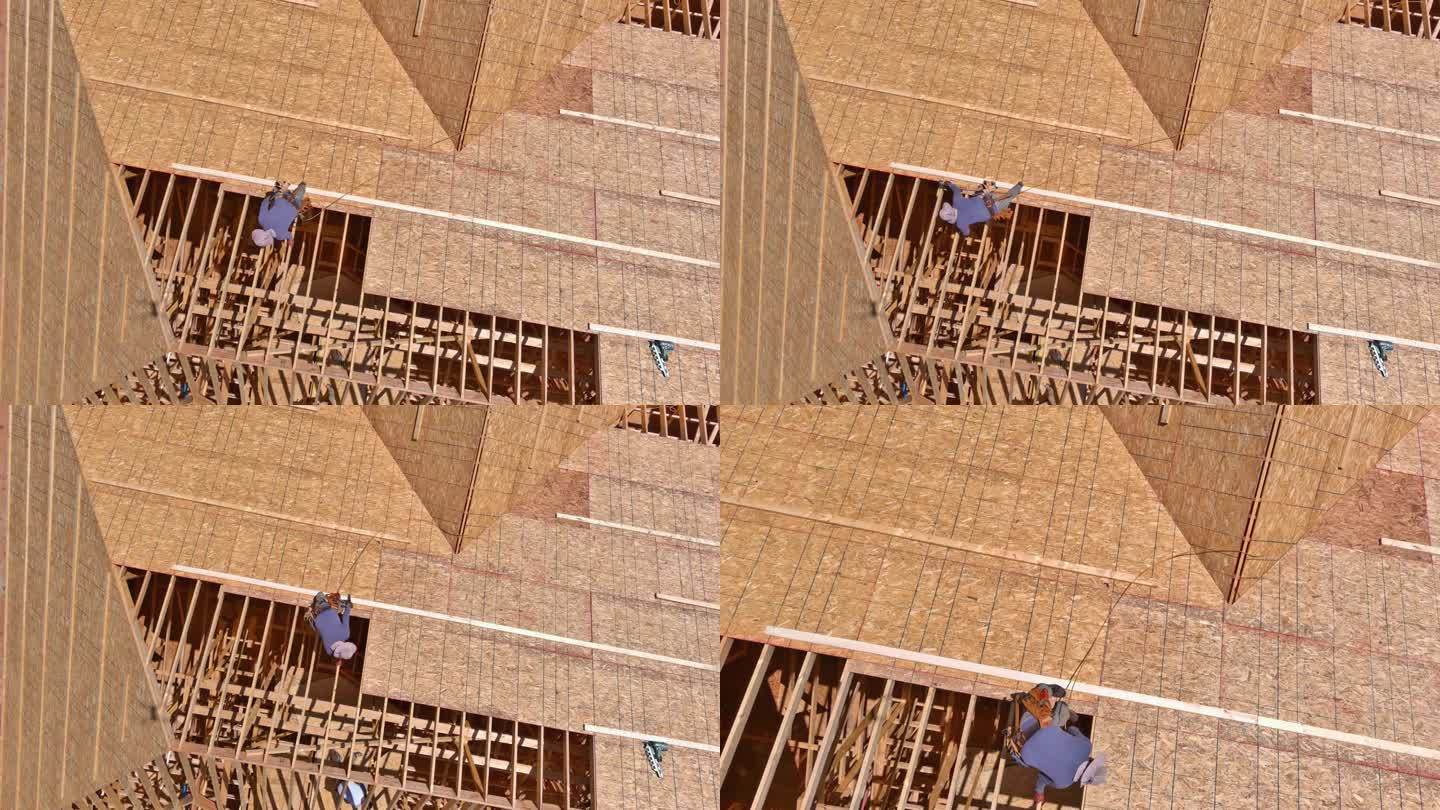 工人将钉子打入未来房屋屋顶的胶合板中