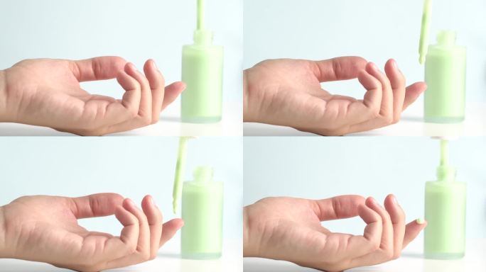 绿色保湿精华液滴在女人的手上，护肤化妆品，保湿凝胶。柔和绿色的精华液或凝胶从移液管滴在干燥的皮肤上。