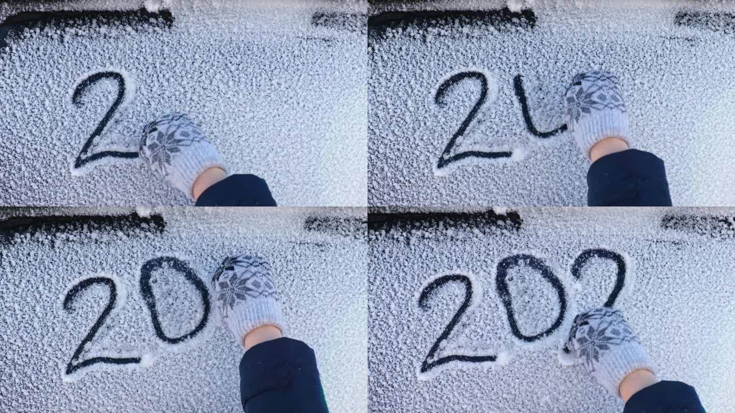 2024年新年假期文字画在雪地上。冬雪的白色表面上刻着2024年的日期。新年和圣诞节的概念。戴着针织