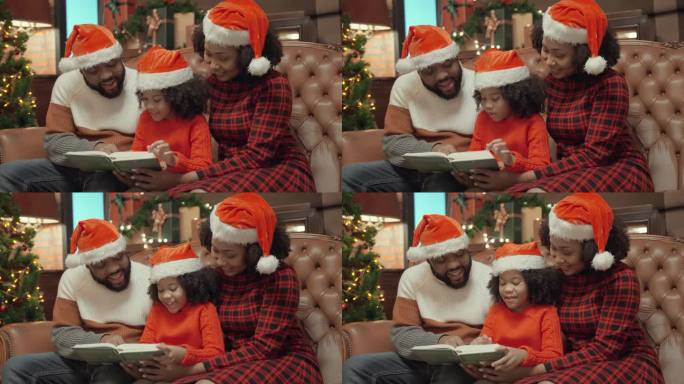 在家里过圣诞夜。漂亮的非洲裔中年美国母亲和父亲戴着圣诞老人的帽子一起给他们的小女儿讲睡前故事。一家人
