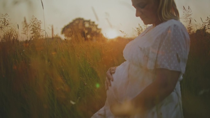 日出时，身着白衣的孕妇坐在田野里