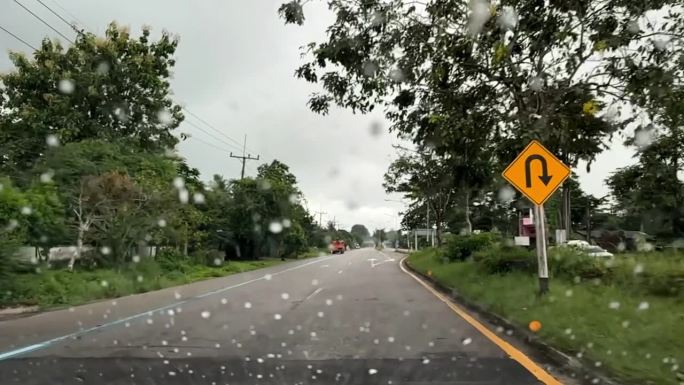 下雨天驾驶的慢动作镜头，选择性聚焦在挡风玻璃上的雨滴。
