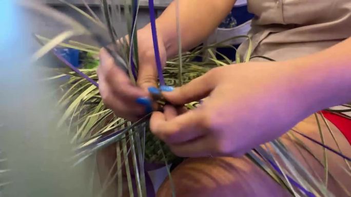 女性手工编织技能，使用干燥和染色的芳香螺旋木或香草草制作农民的帽子。近距离