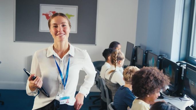 在信息技术课上，微笑的女中学老师与学生在电脑前的合影