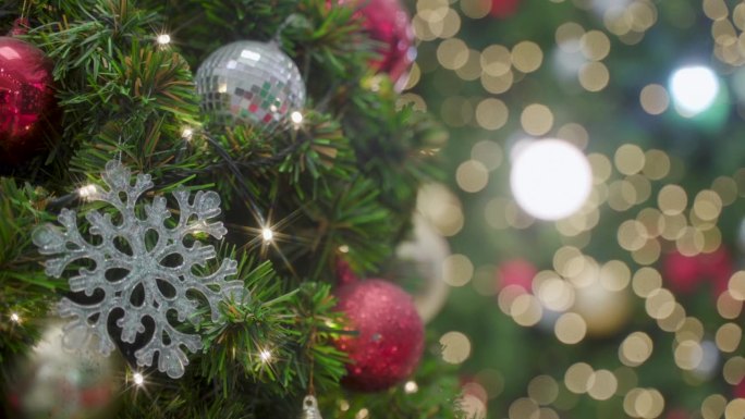 装饰圣诞树。双手用红色小玩意装饰圣诞树，在家里享受节日的装饰