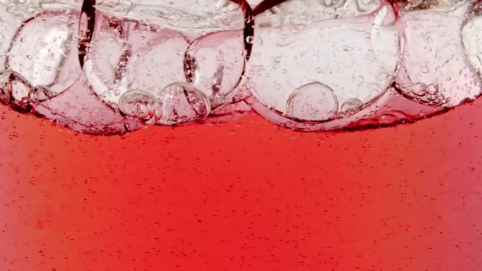 缓慢移动的红油，气泡在水中上升的白色背景。带有气泡的透明化妆品凝胶液。微距镜头。