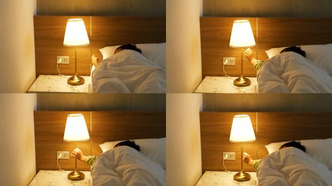 亚洲男孩睡不着，眼睛亮着，用手关掉卧室的床头灯。