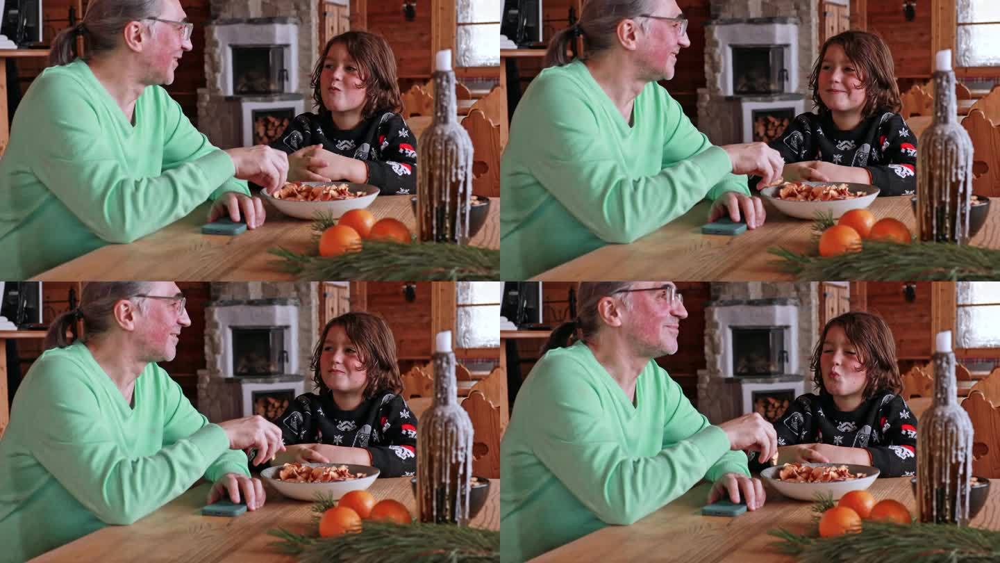 一个头发花白、戴眼镜的成年人和一个男孩坐在餐馆里吃苹果片