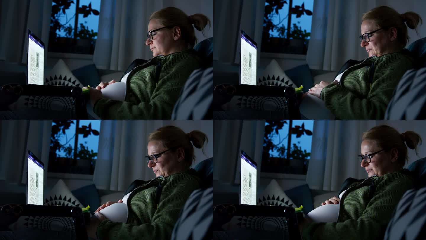 孕妇坐在客厅沙发上使用笔记本电脑