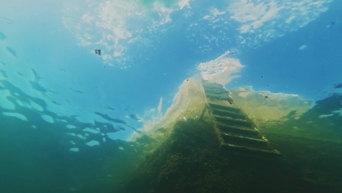 一名女子跳入大海的水下镜头，一名潜水员靠近了她的水下相机