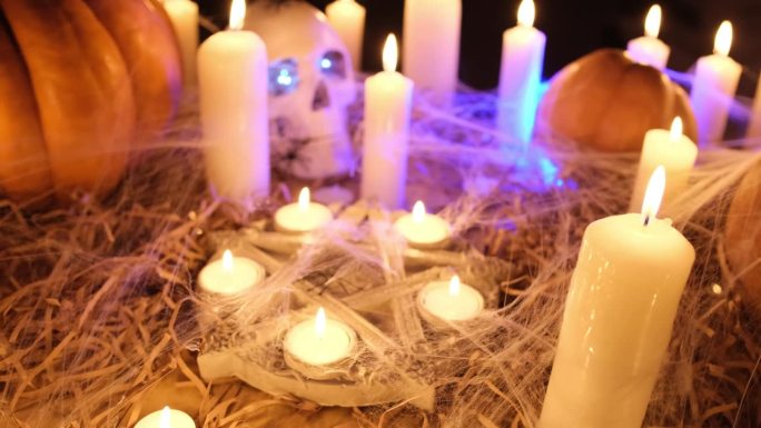 传统的万圣节南瓜配上蜡烛，诡异的骷髅头，在黑暗中，摄像机缓缓追踪神秘的节日背景。