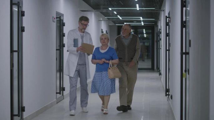 老年夫妇与医生在医疗中心走廊散步