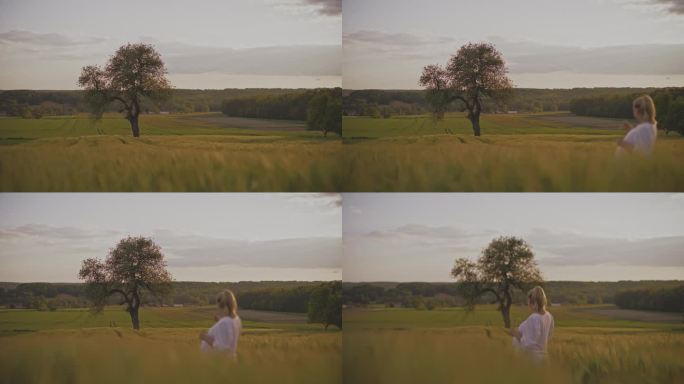 一名孕妇站在田园诗般的、有树的农村麦田里