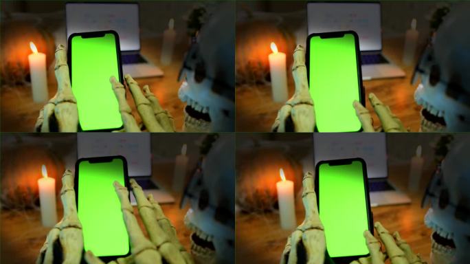 骷髅用瘦骨嶙峋的手指抚摸着智能手机的绿色屏幕