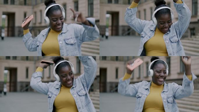 细心的非洲裔美国妇女戴着耳机在户外跳舞，在城市街道上玩耍