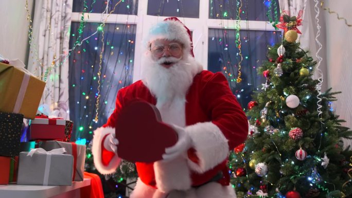 可爱的圣诞老人跳舞抓住心形的礼盒，把它放在胸前