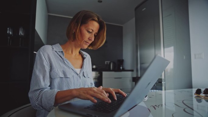 中年成年女性在家工作时使用笔记本电脑