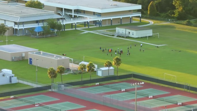 美国学校的体育教育。日落时分，学生们在学校体育馆进行体育锻炼，玩美式足球