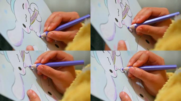 儿童拿着彩笔在绘本上涂画手特写
