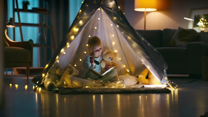 故事，手电筒和泰迪熊带着一个女孩在她家卧室的帐篷里过夜。孩子们，读书或讲故事与年幼的孩子读给她的毛绒