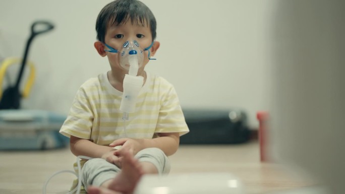儿科保健:患病的亚洲男孩使用雾化器缓解流感和支气管炎。