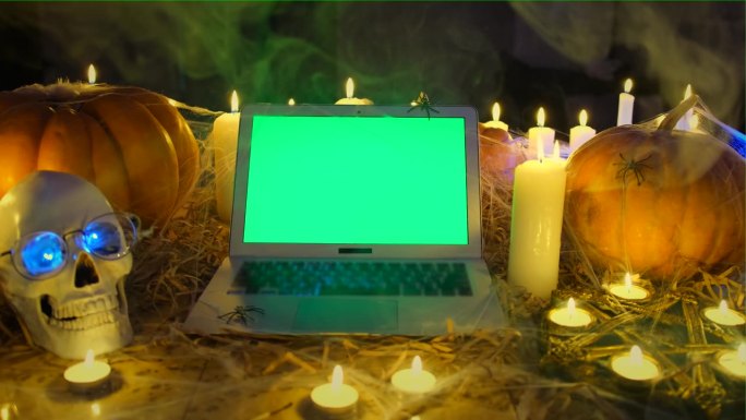 笔记本电脑的色度键绿色屏幕在烟雾中燃烧的蜡烛在地板上。