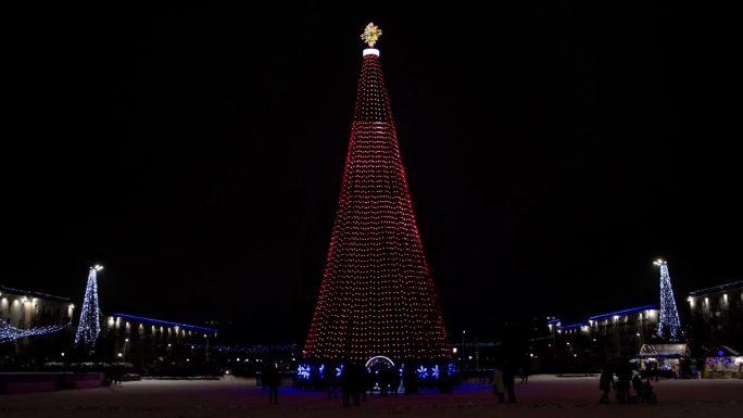 一棵又大又漂亮的新年树挂满了彩灯和装饰品，矗立在城市广场上。许多人晚上在街上庆祝新年。文本复制空间