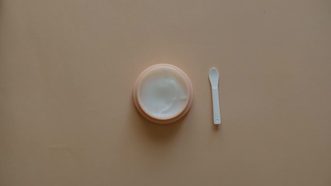 塑料罐的美容霜或面膜护理用抹刀在柔和的背景，俯视图。概念护肤美容，美容spa医疗护肤。天然化妆品概念