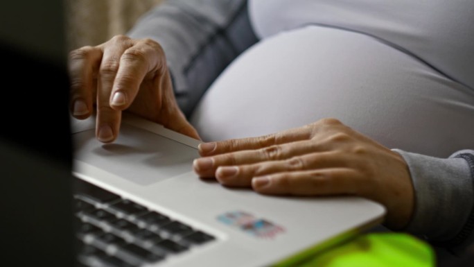 孕妇使用笔记本电脑的近距离双手