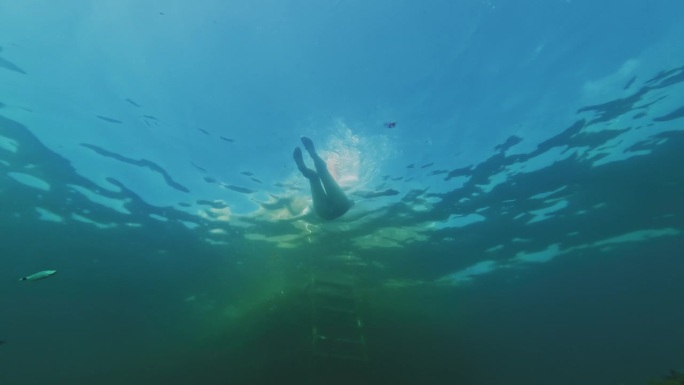 当一名潜水员靠近水下摄像机时，一名女子游回岸边