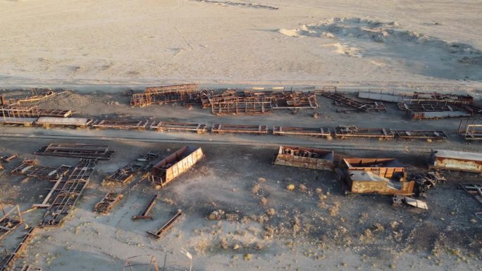 锈迹斑斑的废弃火车车厢躺在沙漠中的铁路线旁