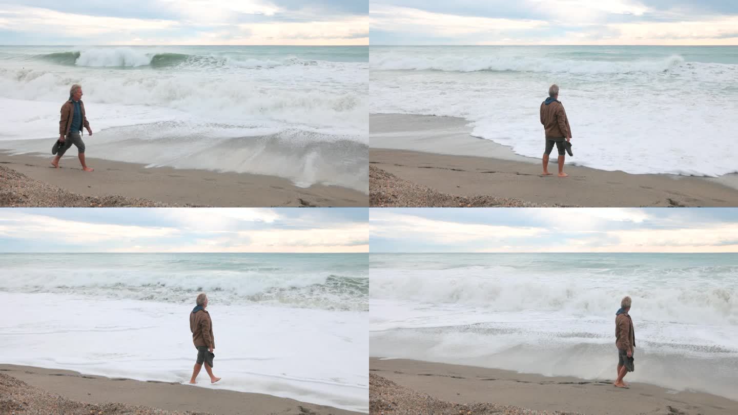 一个成熟的男人走在沙滩上，海浪很大